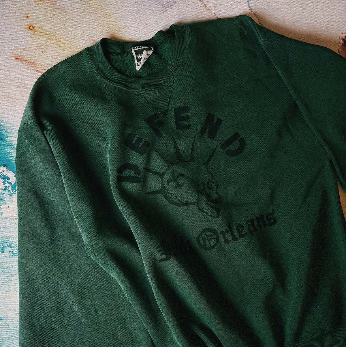 Green sweatshirt with 'Defend' logo on a textured surface
