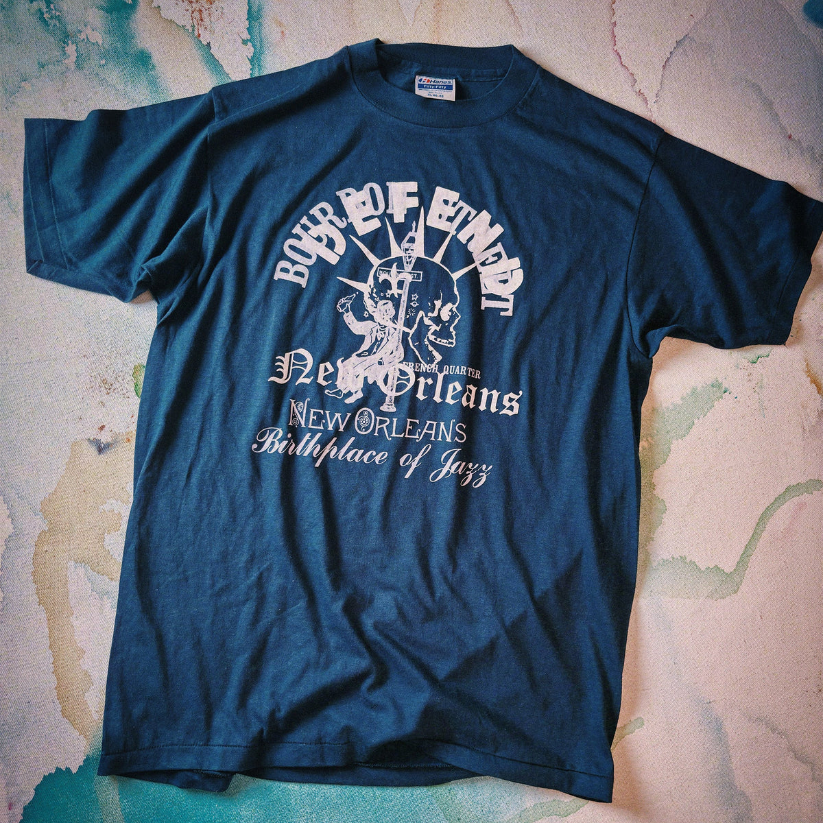 Blue t-shirt with white text and graphics on a textured surface